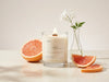 Upsensed Alto clean burning candle with a wooden wick styled with grapefruit slices and soft white florals.