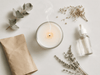 Extinguished candle in a glass jar with lavender, eucalyptus, and dropper bottle representing clean non-toxic ingredients