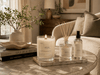 Upsensed Moss candle, reed diffuser, and room spray styled on a marble coffee table in a warm modern living room.