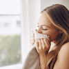 Woman inhaling scent from a towel by a sunlit window, representing the psychology of scent and emotional memory
