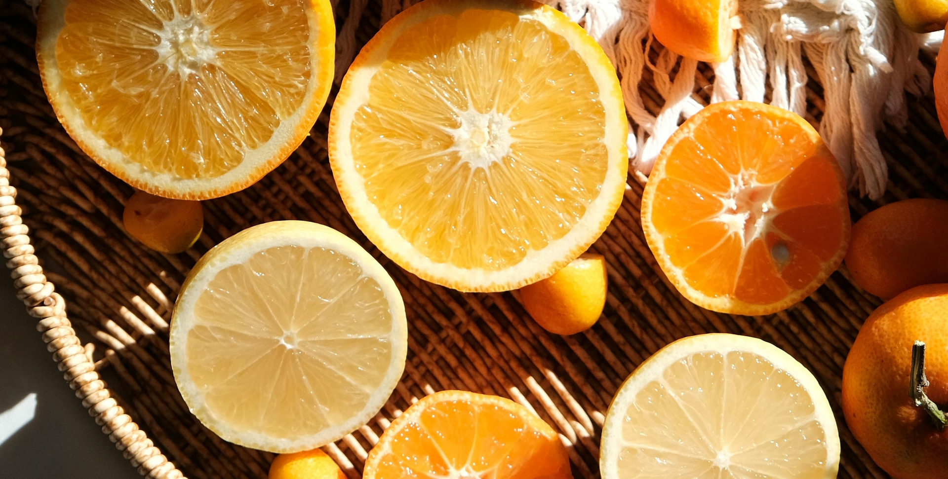 Sliced lemons and oranges on a wicker tray in warm sunlight evoking the Upsensed citrus home fragrance collection