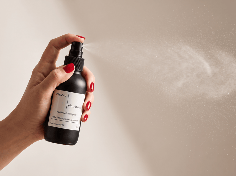 Three Upsensed room + linen sprays — Nocturne, Cloudwash, and Undertow — displayed together on a warm stone surface with a linen cloth, dried floral stem, and smooth stone.