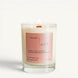 Lit Alto candle in a clear glass jar with a coral label and wooden wick on a clean white background.