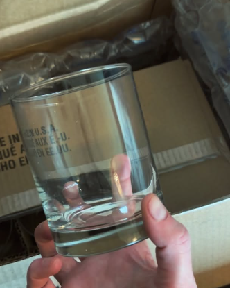 Clear glass candle vessel held during Upsensed product development and packaging preparation.