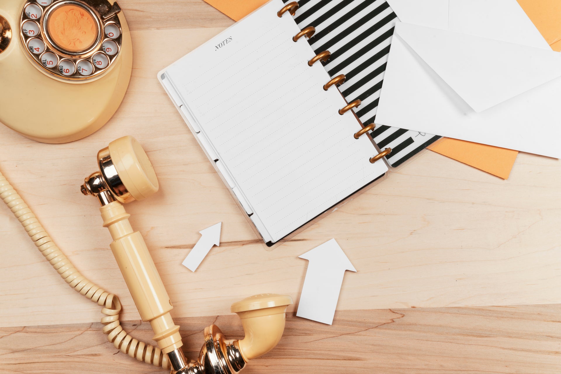 Antique-style phone lying on a wooden table next to a note pad