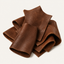 A pile of brown textured leather sheets or strips, arranged in a stack on a clean off-white background.