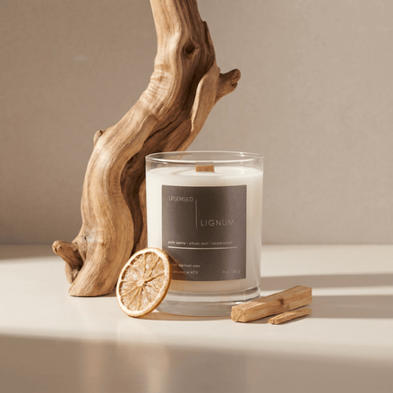 Lignum candle styled with palo santo wood, dried citrus, and natural wood accents on a warm neutral surface.
