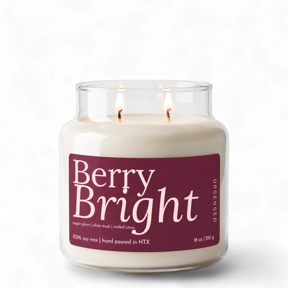 Upsensed Berry Bright 18 oz double-wick soy candle, lit, in a clear apothecary jar with a deep berry label listing sugar plum, white musk, and mulled citrus
