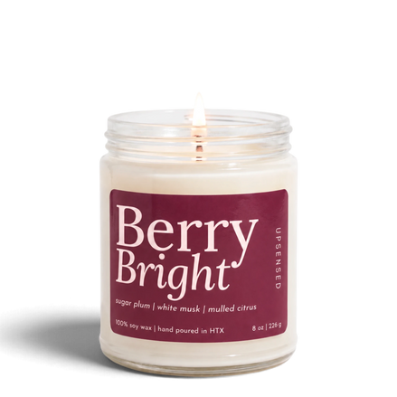 Upsensed Berry Bright 8 oz soy candle, lit, in a clear glass jar with a deep berry label listing sugar plum, white musk, and mulled citrus