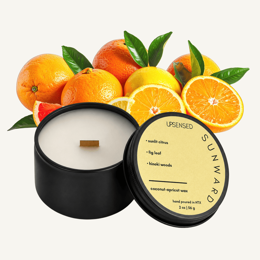  Upsensed Sunward 2 oz mini candle in a matte black tin with golden yellow lid, surrounded by an abundant arrangement of oranges, grapefruits, and lemons