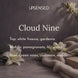 Cloud Nine soy candle fragrance notes: white freesia and gardenia on top, pomegranate, lily, and violet in the middle, and green vines, cashmere, and woods at the base, shown with white lilies, freesia, and a soft oatmeal cashmere throw against a dusky violet-gray backdrop.