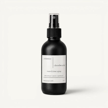 Upsensed Cloudwash room and linen spray in a matte black 4 oz bottle with a white label, cotton blossom, jasmine, and sandalwood scent notes, on a plain white background.