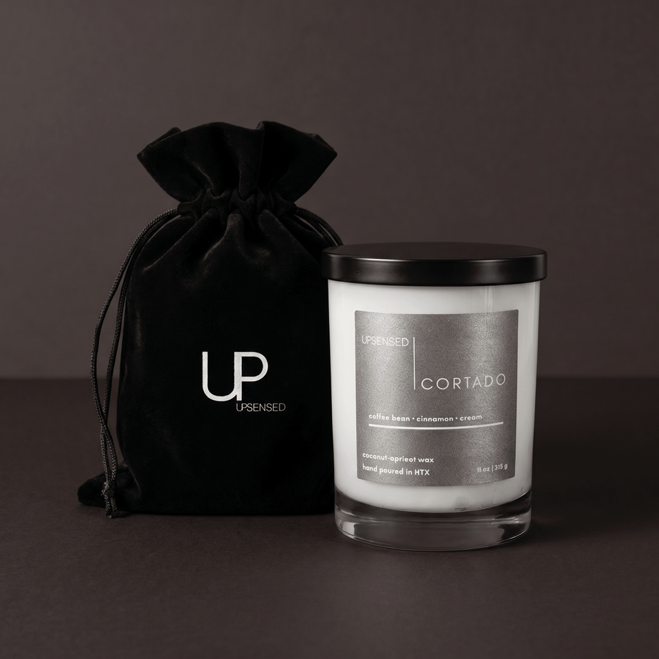 Upsensed Cortado candle beside reusable black velvet drawstring gift bag on dark espresso background