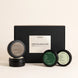 An Upsensed 'Fall Discovery Set' featuring a matte black gift box with a white label, accompanied by four round black cosmetic tins with dark green and off-white labels, arranged on a light beige background.