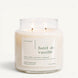 Upsensed Forêt de Vanille 16 oz double-wick candle in a clear apothecary jar with a cream label, creamy vanilla, tonka bean, and cedarwood scent notes, on a plain white background.