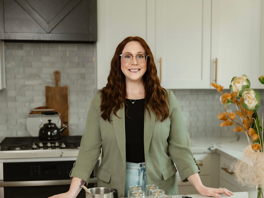 Upsensed founder standing in a kitchen candle-making workspace with glass jars and candle wax supplies on the counter.
