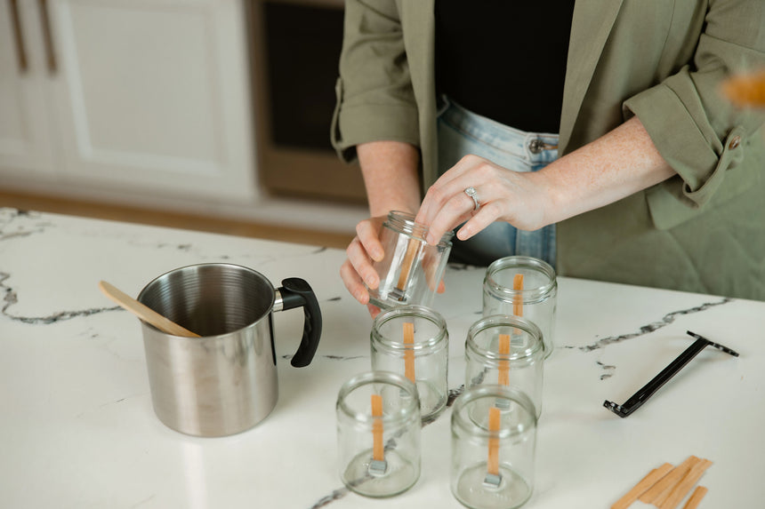Founder preparing clear glass candle jars with wooden wicks for Upsensed hand-poured luxury candles in a modern home fragrance studio.