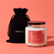 Upsensed Grapefruit + Mint candle with a black lid beside its black velvet UPSENSED drawstring packaging bag, on a coral background.