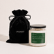 Upsensed Higher Ground candle with a black lid beside its black velvet UPSENSED drawstring packaging bag, on a cream background.