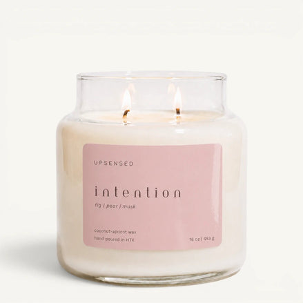 Upsensed Intention 16 oz double-wick candle in a clear apothecary jar with a pink label, fig, pear, and musk scent notes, on a plain white background.