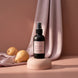 Intention room and linen spray on a blush pedestal with draped mauve satin and two pears.