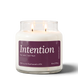 Intention 18 oz double-wick soy candle by Upsensed, both wicks lit, in a clear glass jar with a pink label listing fig, pear, and tart fruit notes.