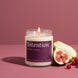 Intention 8 oz soy candle by Upsensed, lit, in a clear glass jar with a fig purple label, beside a halved fig, a halved pear, and red currants on a dusty rose backdrop.