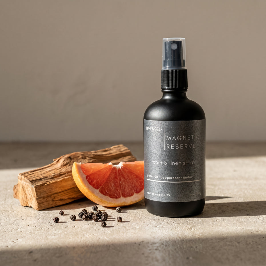 Upsensed Magnetic Reserve Room and Linen Spray beside fresh grapefruit slice cedarwood and black peppercorns - woody citrus home fragrance hand poured in Houston