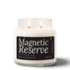 Magnetic Reserve 18 oz double-wick soy candle by Upsensed, both wicks lit, in a clear glass jar with a black label listing Japanese grapefruit, peppercorn, and cedar notes.