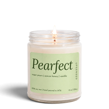Upsensed Pearfect 8 oz soy candle, lit, in a clear glass jar with a pale pear green label listing sugar pears, acacia honey, and vanilla