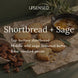 Shortbread + Sage fragrance notes graphic over shortbread cookies on parchment with browned butter, fresh sage leaves, and candied pecans. Top note buttery shortbread; middle notes wild sage, browned butter; base note candied pecan.