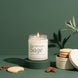 Shortbread + Sage soy candle in an 8 oz glass jar with a cream label, lit on a green pedestal beside a tin of shortbread cookies, scattered pecans, and a sprig of fresh sage against a deep green background