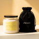 Upsensed Sunflowers + Citrus candle with a black lid beside its black velvet UPSENSED drawstring packaging bag, on a warm golden background.