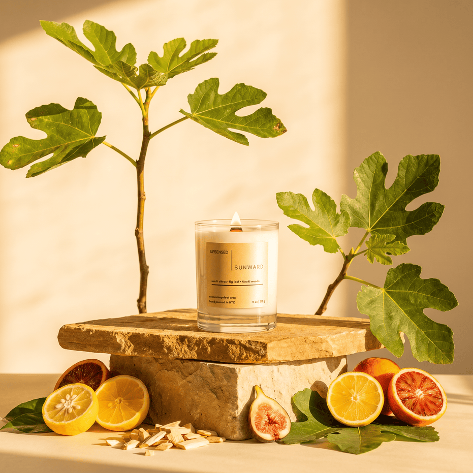Upsensed Sunward candle on a stone pedestal surrounded by sliced citrus, fresh figs, fig leaves, and hinoki wood chips