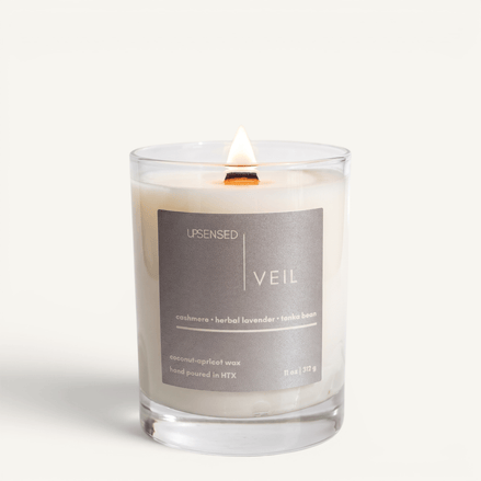 Upsensed Veil candle lit on white background, showing silver-grey label with cashmere, herbal lavender, and tonka bean notes