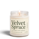 Upsensed Velvet Spruce 8 oz soy candle, lit, in a clear glass jar with an ivory label and deep green lettering listing spruce, custard, vanilla, and sandalwood