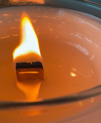 Lit wooden wick burning in creamy coconut-apricot wax